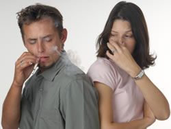 Young lady covering her nose from smoke by a male smoker.